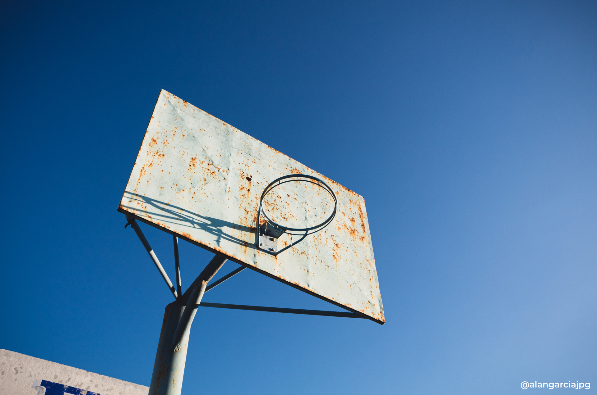 Vieja y oxidada canasta de baloncesto con un cielo azul.